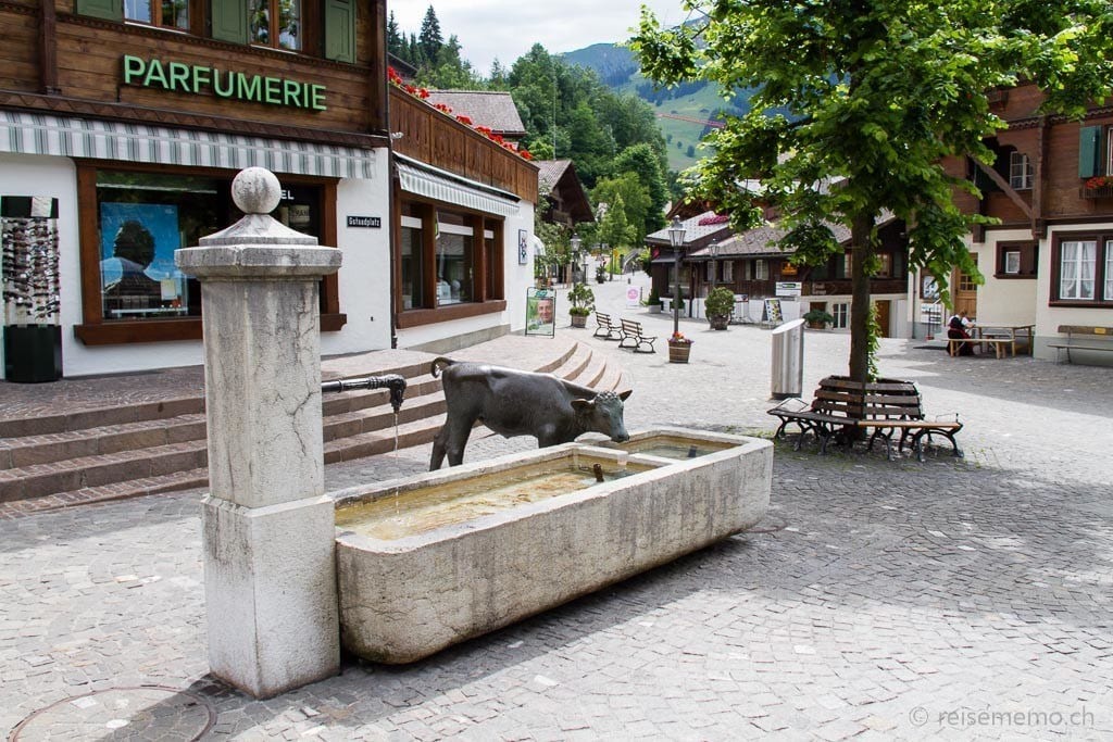 Gstaad Brunnen Kuh Skulptur bei Reisememo