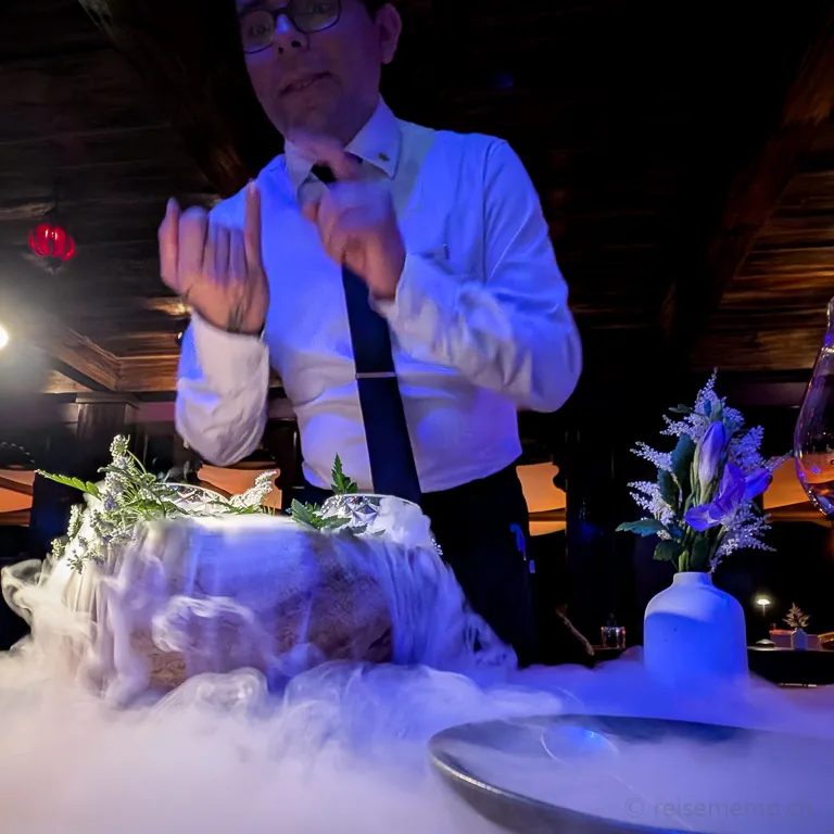 Kellner Sergio im Amor Loco Restaurant in Nayara Gardens: Kellner erläutert Gericht mit dampfendem Trockeneis, während weisser Nebel über den Tisch strömt