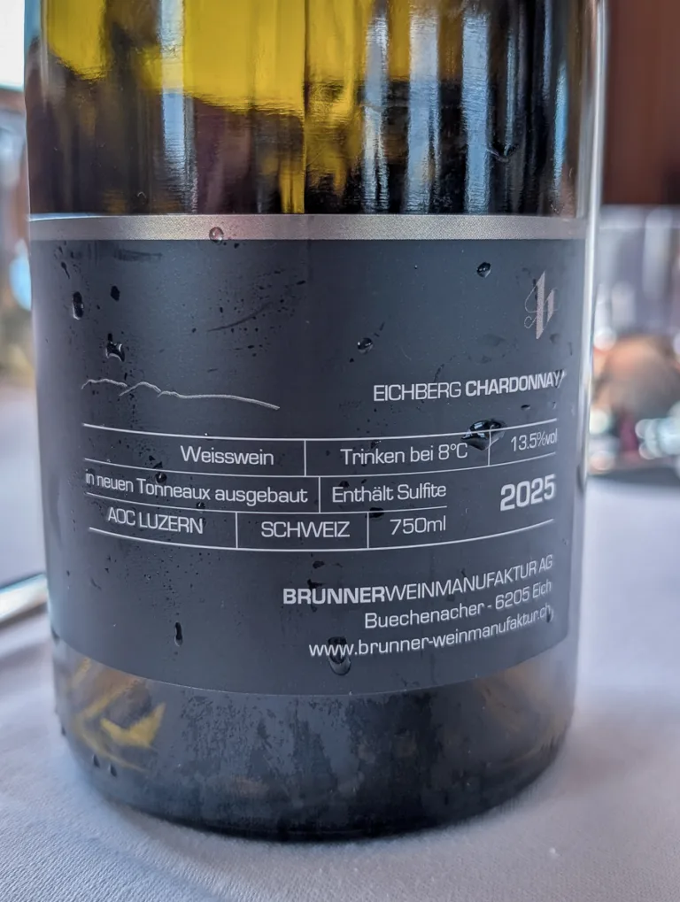 Etikett einer Flasche Eichberg Chardonnay vom Luzerner AOC aus der Brunner Weinmanufaktur auf einem gedeckten Tisch