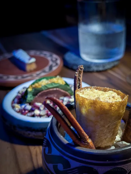 Elegante Dessertpräsentation mit Schokoladentarte, bunten Bohnen und Zimtstangen auf weissem Teller