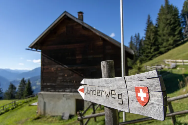 Wanderwegweiser aus Holz mit Schweizerkreuz